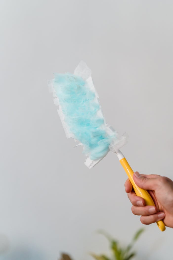 services-03 A close-up of a hand using a Swiffer for indoor cleaning, showcasing cleanliness and efficiency.