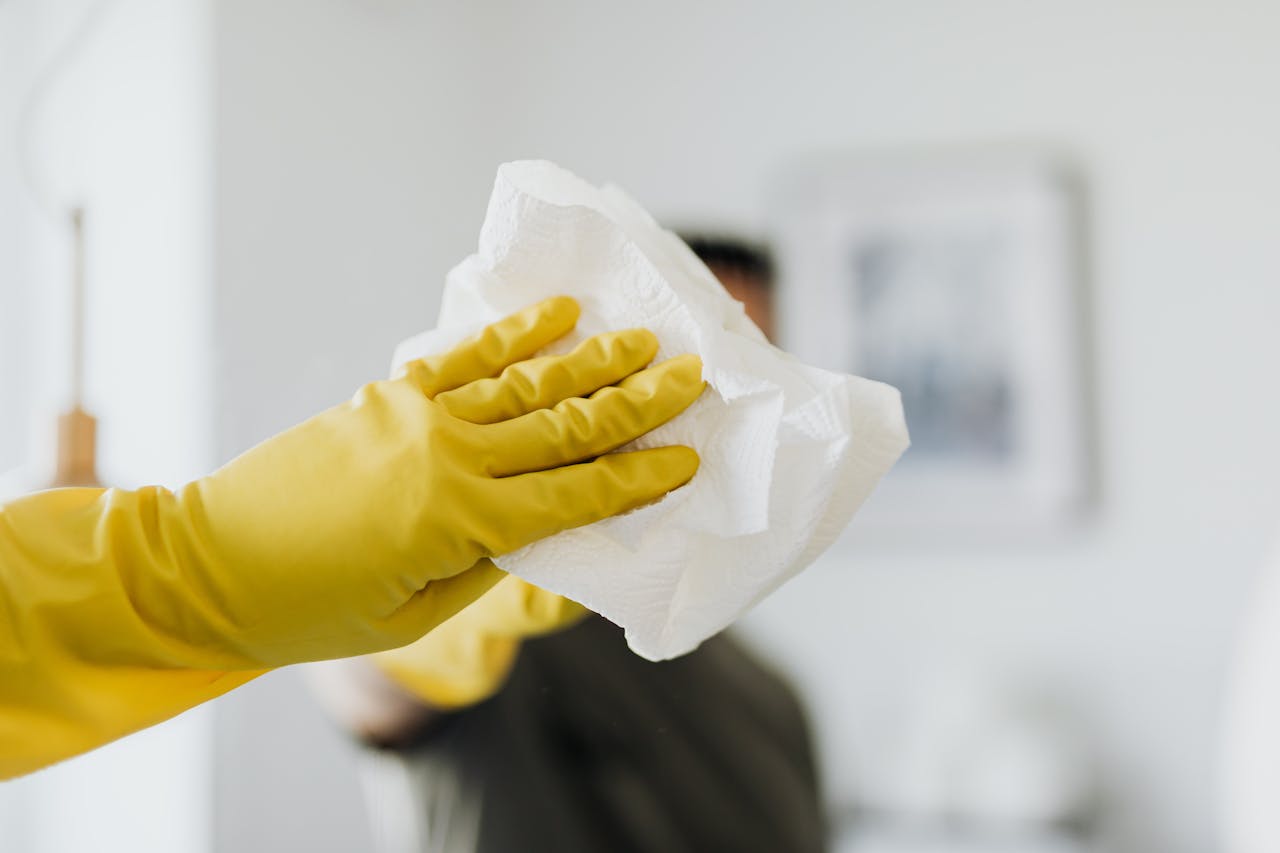 hero-img Faceless male wearing yellow latex gloves and wiping mirror with paper napkin in bathroom while cleaning and disinfects house