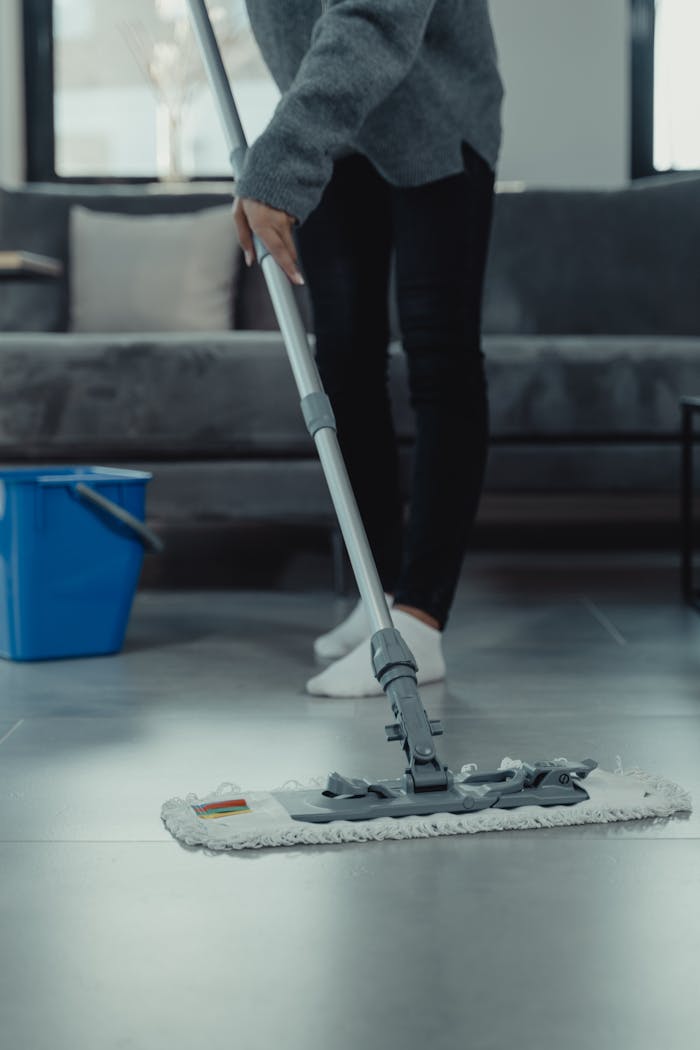 services-01 Close-up of person mopping a clean tile floor in a contemporary living room.
